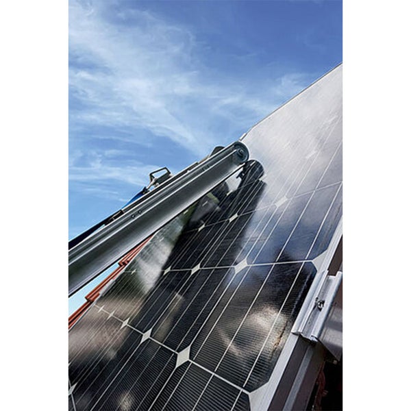 Solarpanel Reinigungssystem mit Reinigungsbürste auf einem auf einem Schrägdach montierten Solarmodul bei sonnigem Himmel.