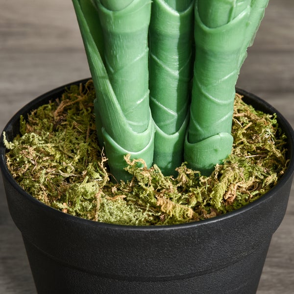 Nahaufnahme der Stiele einer künstlichen Pflanze in einem schwarzen Topf mit Moos.