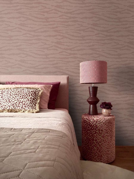 Schlafzimmer mit gemusterter Tapete und Bett mit Kissen, Nachttisch mit Tischlampe und dekorativer Vase, moderne Einrichtung.