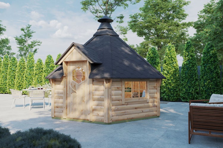 Traditionelle Grillkota aus Holz mit Schindeldach und Schornstein auf einer hellen Terrasse umgeben von Bäumen und Gartenmöbeln.