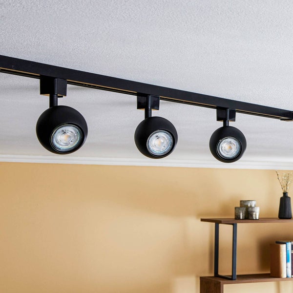 Schwarzes Schienensystem mit drei kugelförmigen LED Strahler an der Decke eines modern gestalteten Wohnraums.