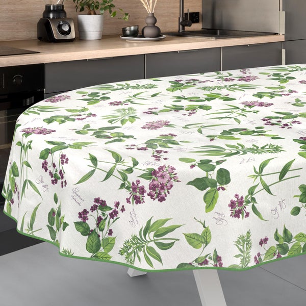 Ovale Tischdecke mit botanischem Muster aus Blumen und Blättern auf einem Tisch in einer hellen, modernen Küche.