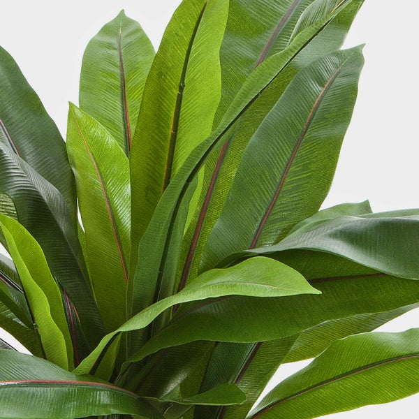 Detailansicht einer Kunstpflanze mit langen grünen Blättern und rötlichen Blattadern.