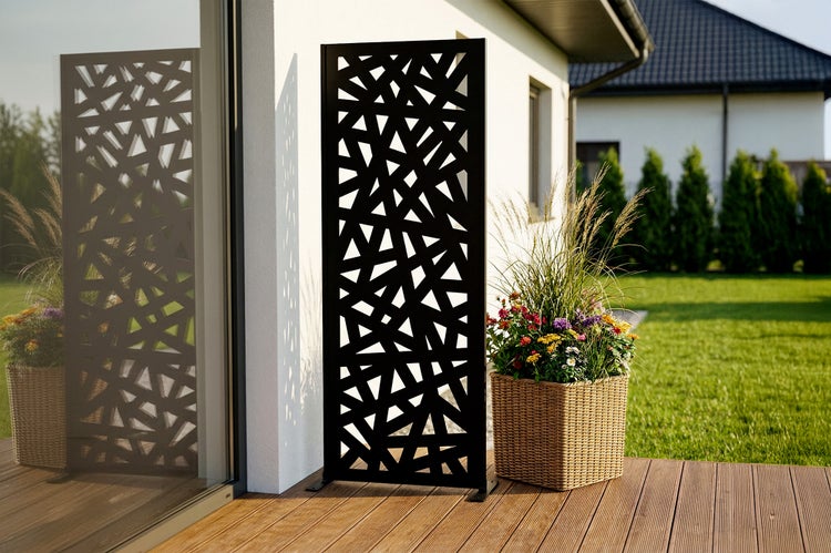 Dekorativer Sichtschutz aus Metall mit geometrischem Muster auf einer modernen Terrasse neben einem Blumenkübel.