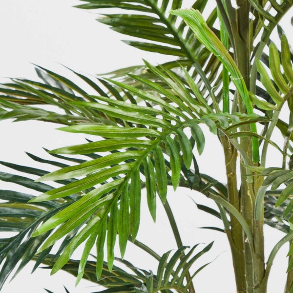 Nahaufnahme einer künstlichen Palme mit grünen Palmwedeln und strukturiertem Stamm.
