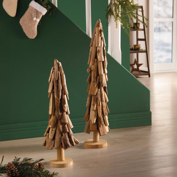 Zwei dekorative Weihnachtsbäume aus Treibholz auf einem Holzsockel in einer weihnachtlich dekorierten Wohnumgebung.