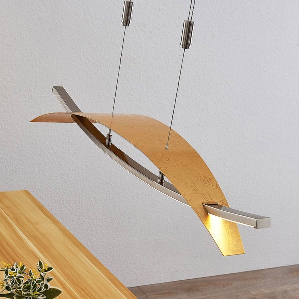 Moderne LED Pendelleuchte über einem Holztisch, gebogener Schirm in Blattgold Optik, Metallgestell, höhenverstellbar.
