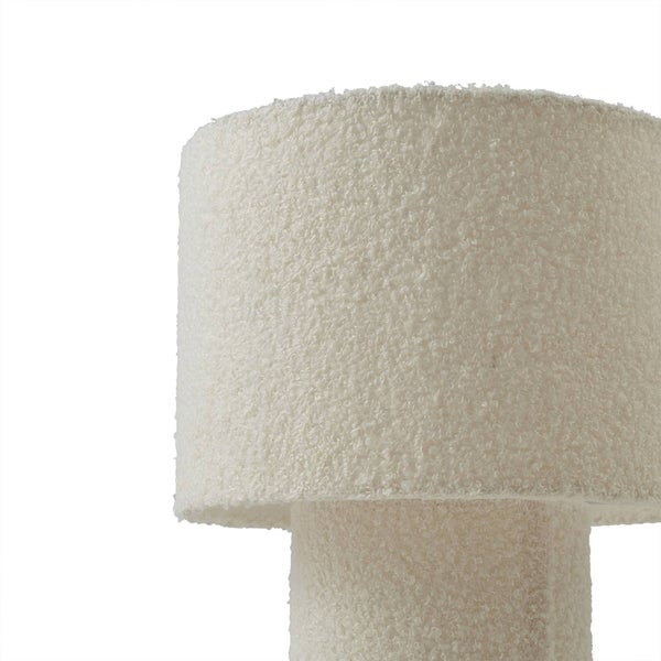 Detailaufnahme einer Tischleuchte mit Lampenschirm und Fuß aus Bouclé-Stoff.