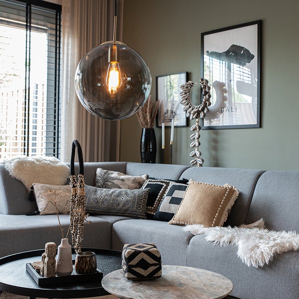 Wohnzimmer mit grauer Eckcouch, Zierkissen, Couchtischen und einer runden Hängelampe