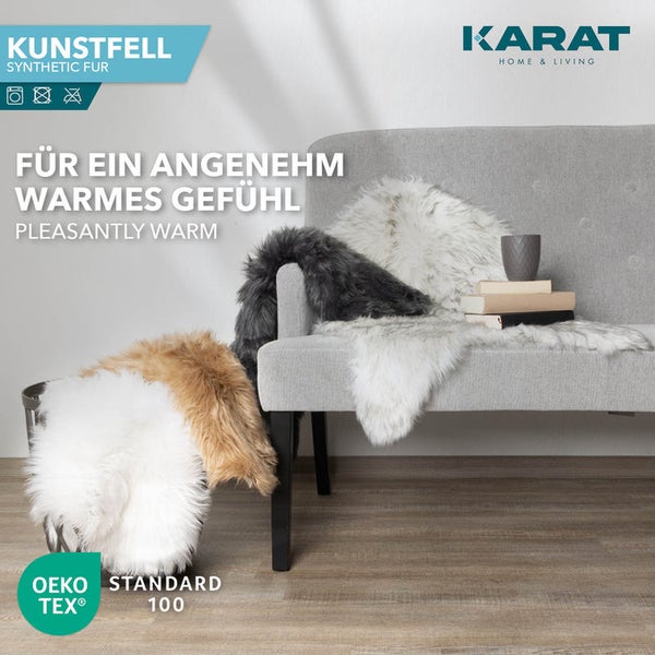 Kunstfell in verschiedenen Farben auf einem grauen Sofa und in einem Korb, Karat Home & Living Logo, Oeko-Tex Standard 100.