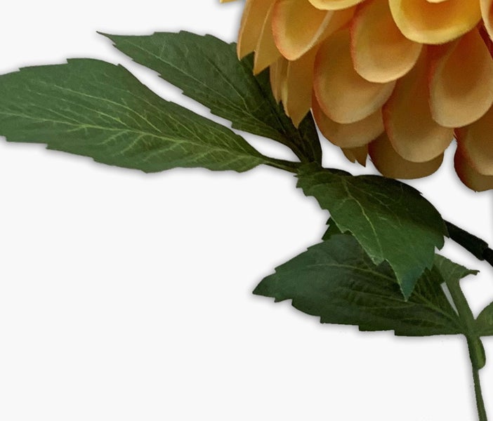 Detailansicht einer künstlichen Dahlie mit strukturierten grünen Blättern und gelben Blütenblättern.