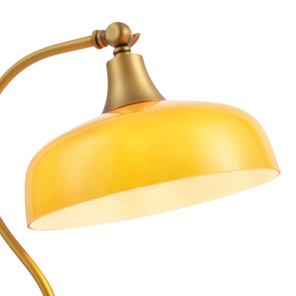 Detailansicht einer Lampe mit gelbem Glasschirm und einem bogenförmigen Metallarm in Messingoptik.