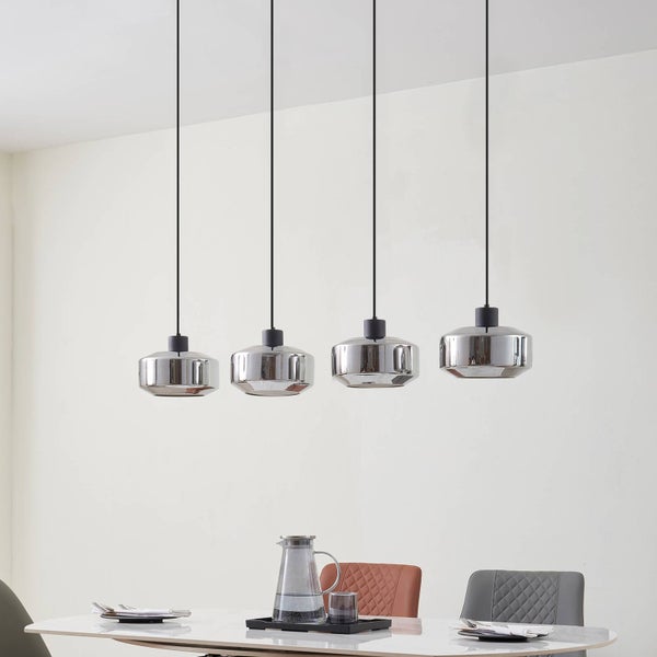 Vierflammige Pendelleuchte mit verchromten Glasschirmen über einem weißen Esstisch in einem hellen Raum.