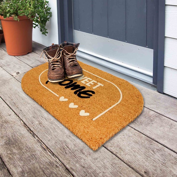 Fußmatte mit Schriftzug Sweet Home und Schuhpaar vor einer Haustür
