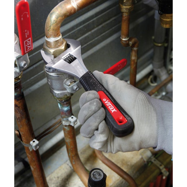 Eine Person benutzt einen verstellbaren Schraubenschlüssel von Virax an einer Kupferrohrleitung.