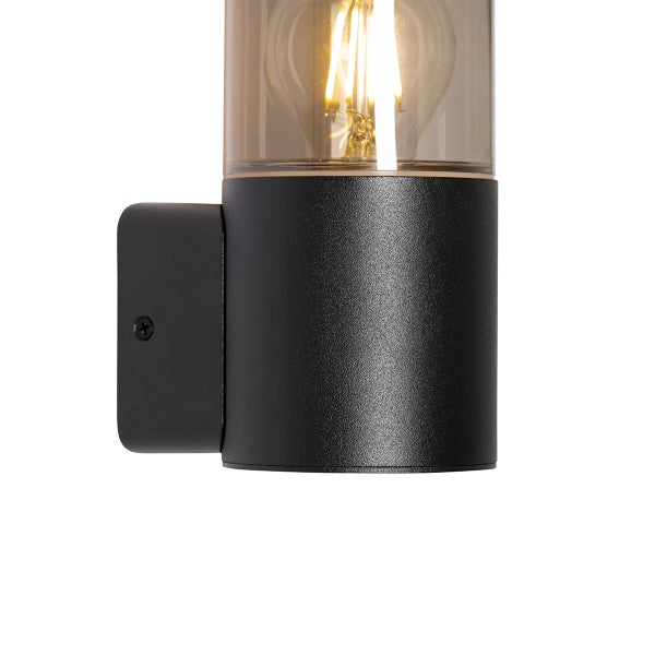 Außenwandleuchte aus schwarzem Metall mit getöntem Glaszylinder und sichtbarem Filament-Leuchtmittel.