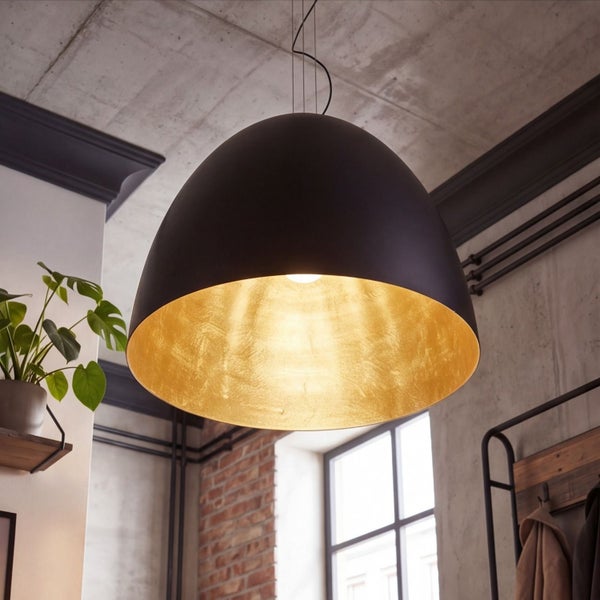Schwarze Metall-Pendelleuchte in Halbkugelform mit goldfarbener Innenseite in einem hellen Raum im industriellen Stil mit Beton und Ziegeln.