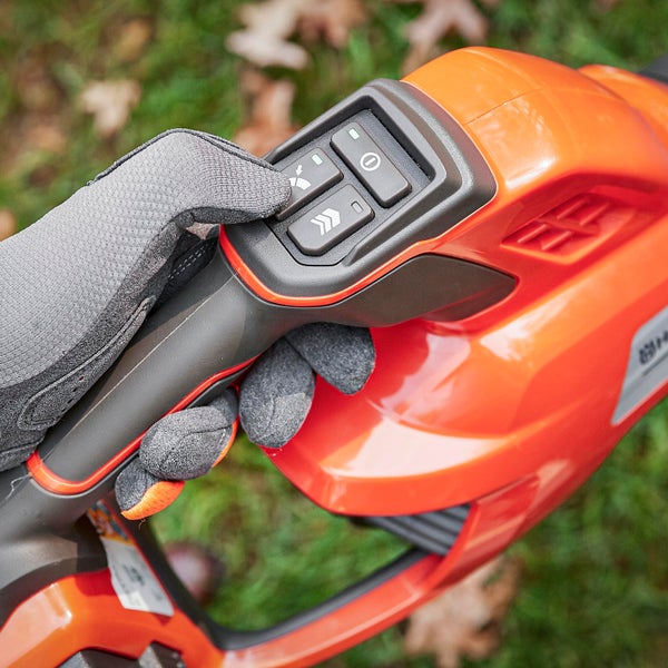 Bedienfeld einer Heckenschere mit Hand in Schutzhandschuh