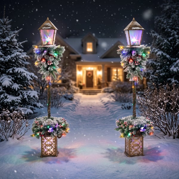 Zwei beleuchtete weihnachtliche Gartenlaternen auf Sockeln mit künstlichen Tannenzweigen und Lichterketten in einer verschneiten Vorgartenszene.