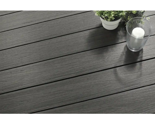 Terrassendiele aus Holz-Kunststoff-Verbundwerkstoff mit Holzmaserung in Anthrazit, dekoriert mit kleiner Pflanze und Kerze in einem Glas.