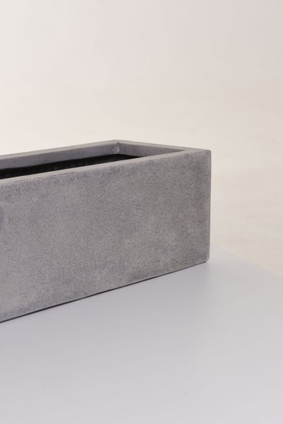 Rechteckiger Pflanzkasten in grauer Beton-Optik mit strukturierter Oberfläche.