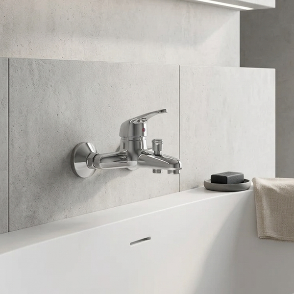 Wandmontierte Badewannenarmatur aus Chrom mit Einhandmischer und Umsteller, montiert an einer Wand in Steinoptik über einer weißen Badewanne.