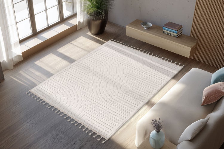 Wohnzimmer mit hellem Teppich mit geometrischem Linienmuster und Quasten auf Holzboden in einem modern eingerichteten Raum mit Sofa.