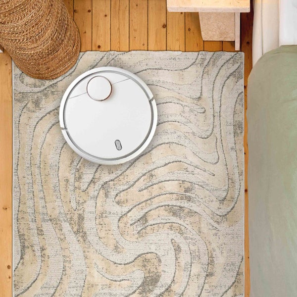 Ansicht von oben: Saugroboter auf einem Teppich mit Muster.