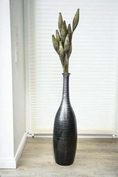 Hohe Bodenvase mit feiner Linienstruktur und dekorativen Trockenpflanzen in einem modern gestalteten Wohnraum.
