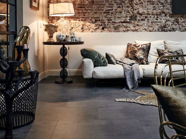 Wohnzimmer mit dunklen Fliesen im Industriestil, kombiniert mit einer Backsteinwand und einem hellen Sofa in einem stilvoll eingerichteten Raum.