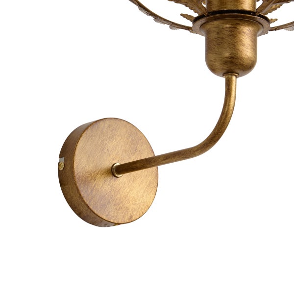 Wandleuchte aus Metall mit antikem Goldfinish, Detail von runder Wandhalterung, geschwungenem Arm und Fassung.