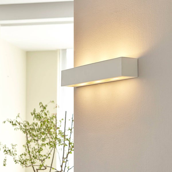 Moderne rechteckige Wandleuchte mit Lichtaustritt nach oben und unten an einer strukturierten Wand in einem hellen Innenraum.