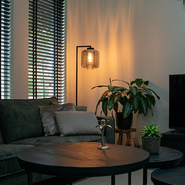 Wohnzimmer mit Sofa, Couchtisch, Stehlampe und Zimmerpflanzen