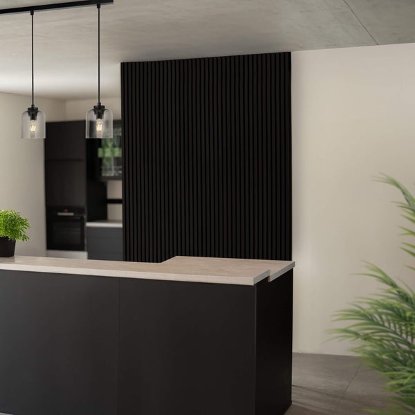 Moderne Pendelleuchten über einer Küchentheke mit schwarzer Lamellenwand in einem minimalistischen Wohnraum.