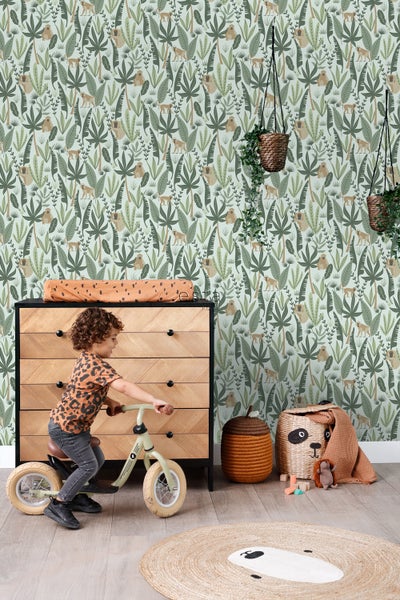 Kinderzimmer mit Dschungeltapete, Kommode, Laufrad und dekorativen Aufbewahrungskörben.