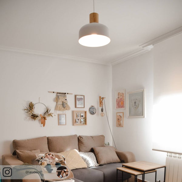 Helles Wohnzimmer im skandinavischen Stil mit beigem Sofa, Satztischen aus Holz und Bilderwand. Eine graue Pendelleuchte mit Holz hängt mittig.