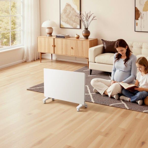 Eine Mutter und ihre Tochter sitzen in einem hellen Wohnzimmer auf einem Teppich neben einem weißen, fahrbaren Heizkörper und lesen ein Buch.