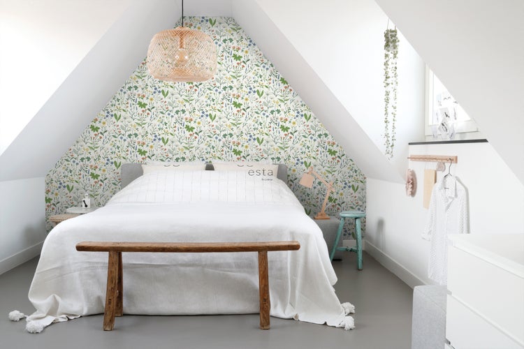 Schlafzimmer im Dachgeschoss mit floraler Tapete, Bett und Holzbank