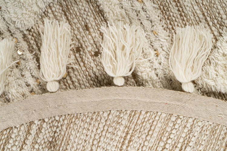 Nahaufnahme eines gewebten Teppichs mit Quasten, strukturierter Oberfläche und goldfarbenen Pailletten.