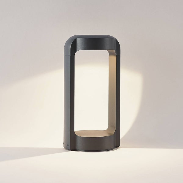 Moderne Außenstandleuchte mit rechteckigem Rahmen, abgerundeter Oberseite und offener Mitte, die warmes Licht wirft.