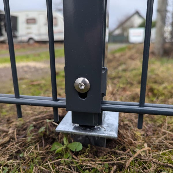 Detailansicht eines Metallzaunpfostens mit Bodenbefestigung