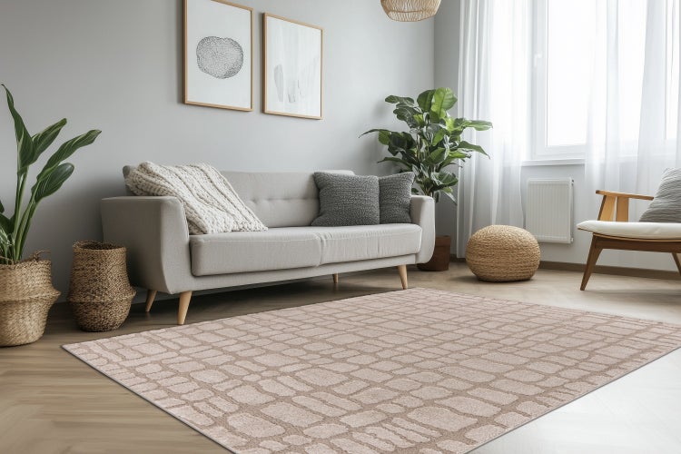 Heller Wohnraum mit einem modernen Teppich in Steinoptik vor einem Sofa, ergänzt durch Zimmerpflanzen, Holzstühle und dekorative Wandbilder.