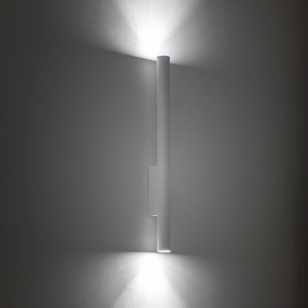 Minimalistische zylindrische Wandleuchte mit Lichtkegeln nach oben und unten an einer Wand.