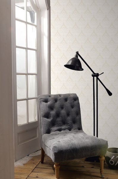 Szene mit einem grauen Sessel, einer Stehlampe und einer Tapete mit Muster