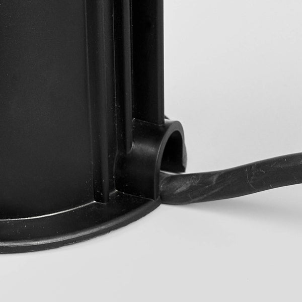 Nahaufnahme eines schwarzen Kunststoffsockels mit seitlicher Kabeldurchführung und eingeführtem Kabel.