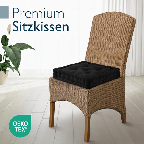 Schwarzes, gestepptes Premium Sitzkissen auf einem Rattanstuhl, OEKO-TEX Zertifikat für schadstoffgeprüfte Textilien.