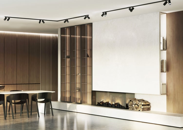 Heller, moderner Raum mit Einbaukamin, Holzstapel, beleuchteter Glasvitrine, Esstisch, Holzpaneelen und schwarzem Schienensystem an der Decke.