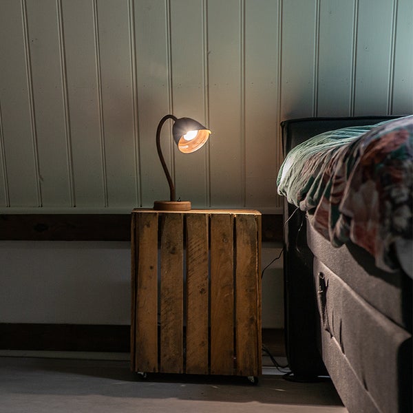 Nachttisch aus Holzkiste mit Tischleuchte im Schlafzimmer