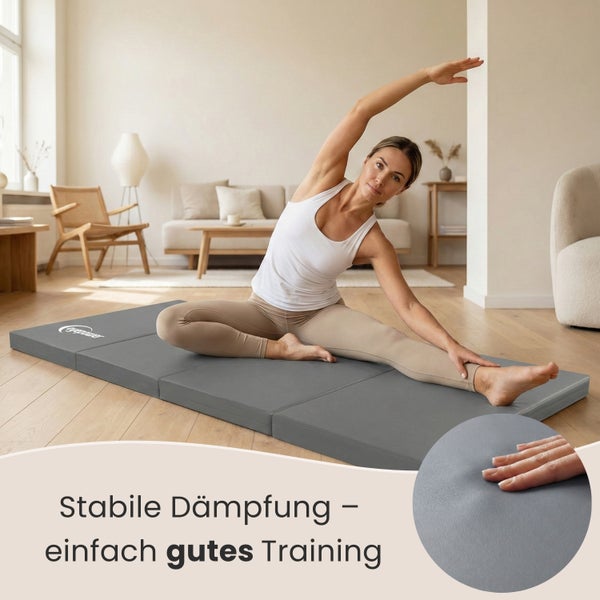 Frau dehnt sich auf einer grauen Gymnastikmatte im Wohnzimmer