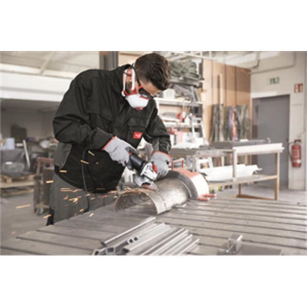 Ein Handwerker nutzt einen Winkelschleifer, um Metall in einer Werkstatt zu bearbeiten, während er persönliche Schutzausrüstung trägt.